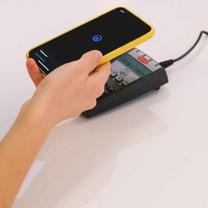 Pessoa fazendo pagamento pelo WhatsApp com o celular em uma maquininha