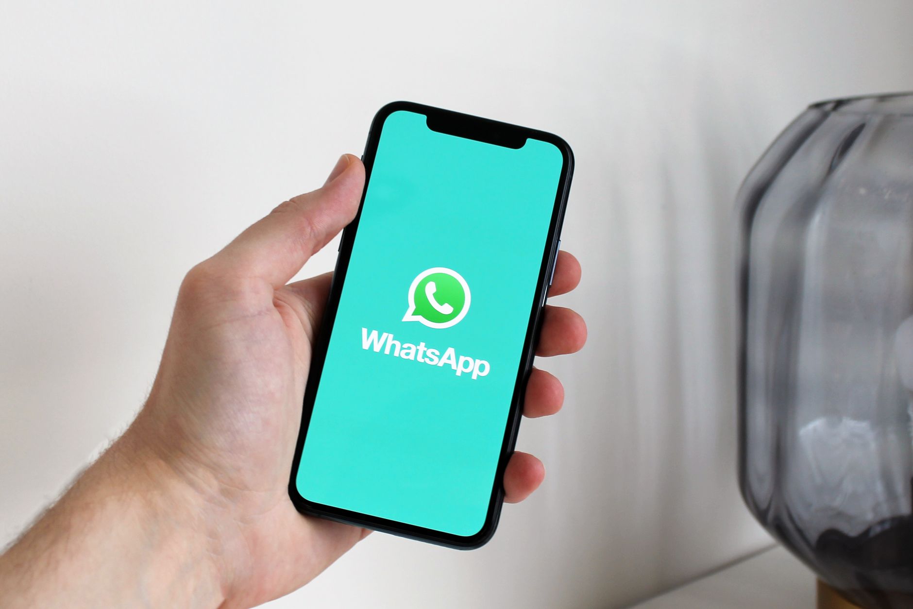 em Pessoa segurando smartphone com WhatsApp aberto, representando integração via API oficial