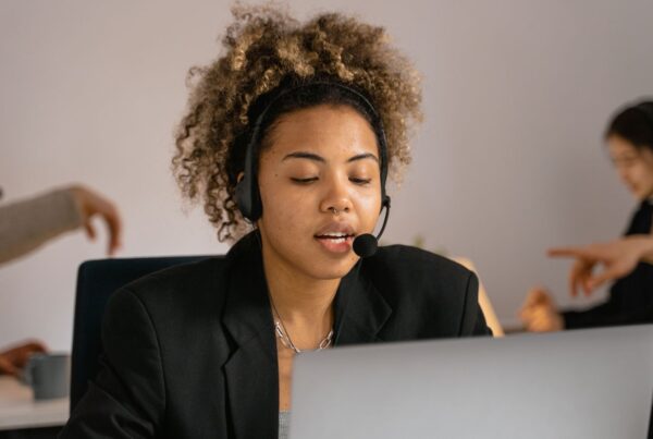 Atendente com headset trabalhando no notebook em uma operação de atendimento humano e IA no WhatsApp