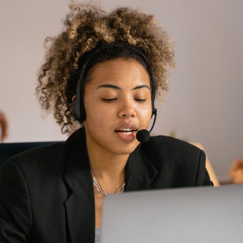 Atendente com headset trabalhando no notebook em uma operação de atendimento humano e IA no WhatsApp