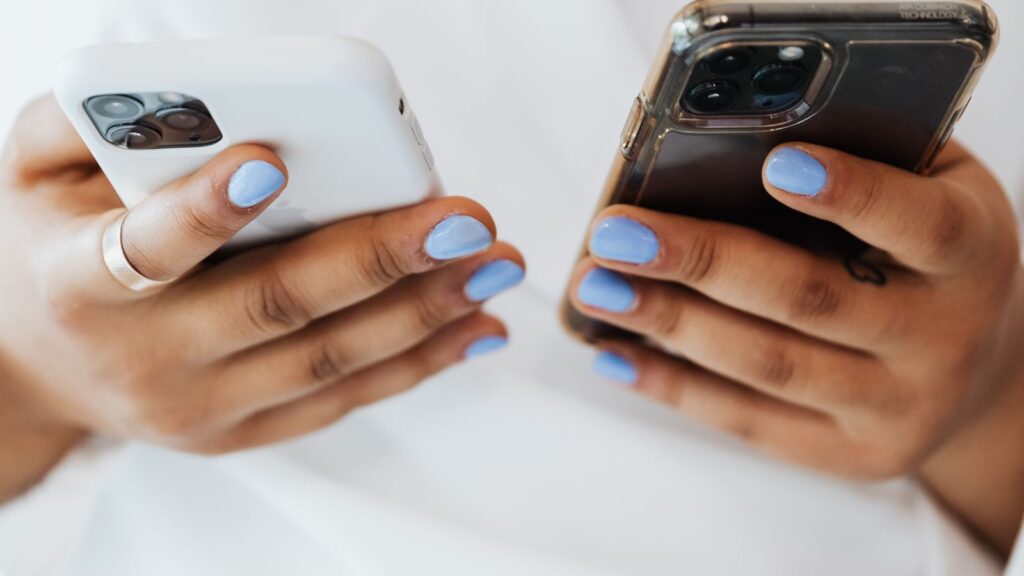 Mãos segurando dois celulares, representando a Conexão Híbrida WhatsApp entre API Oficial e conexão não oficial