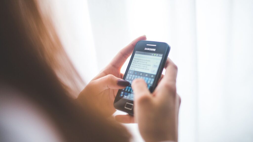 Mulher digitando no celular, representando o envio de templates WhatsApp Business aprovados