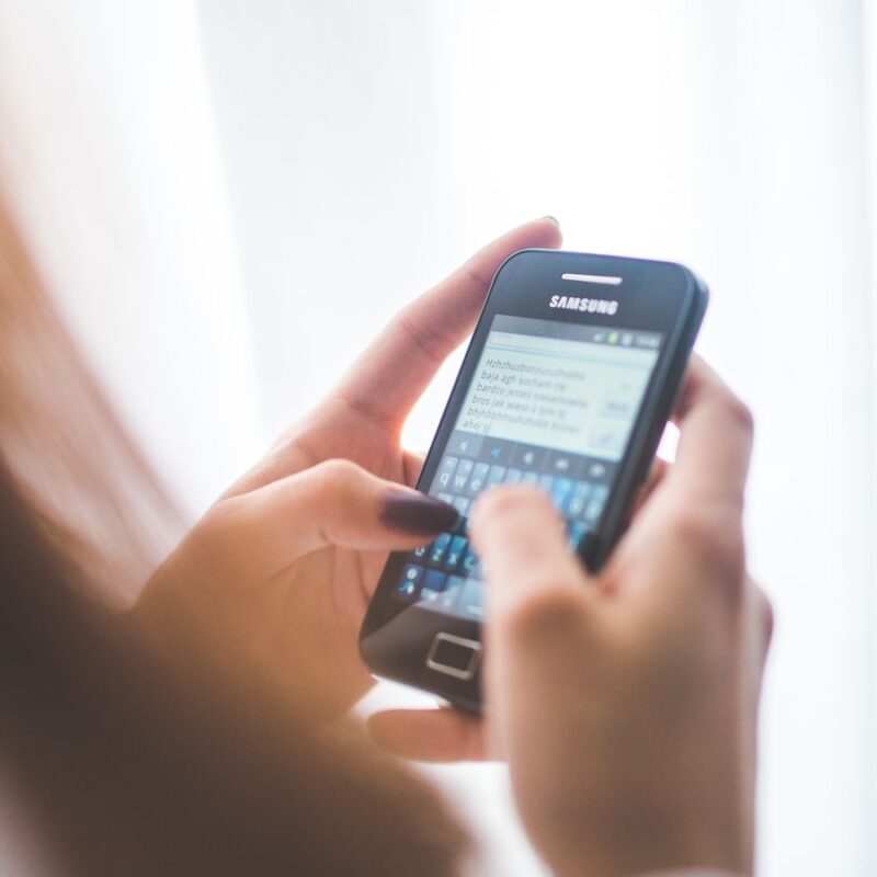 Mulher digitando no celular, representando o envio de templates WhatsApp Business aprovados